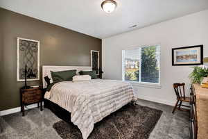 Primary bedroom with dark colored carpet and baseboards