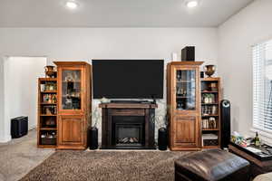 Carpeted living room with a fireplace and recessed lighting