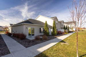 View of property exterior featuring a lawn, stucco siding, and a residential view