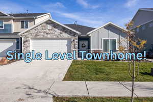 View of front of house with a front yard, stone siding, and concrete driveway and 2 car garage
