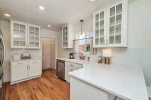 Kitchen featuring glass insert cabinets, white cabinetry, recessed lighting, light wood-style flooring, and hanging light fixtures