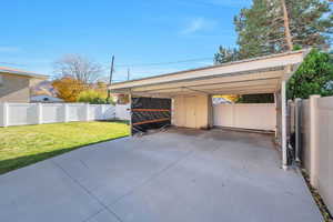 View of vehicle parking featuring a fenced backyard, a carport, and driveway
