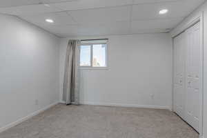 Unfurnished bedroom featuring light carpet, a closet, a drop ceiling, and recessed lighting