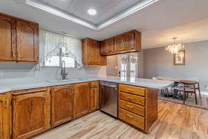 Kitchen featuring a peninsula, brown cabinetry, light countertops, light wood finished floors, and recessed lighting