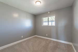 Carpeted empty room featuring baseboards and a textured ceiling