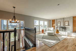 Living area featuring a chandelier, a textured ceiling, wood finished floors, and a brick fireplace