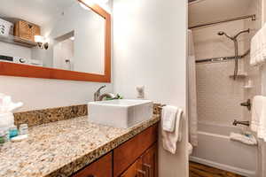 Bathroom featuring vanity, shower / tub combo with curtain, and dark wood-style flooring