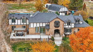 View of front of property with brick siding, a patio, a gazebo, a chimney, and a shingled roof