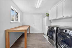 Washroom with light wood-type flooring, separate washer and dryer, and cabinet space