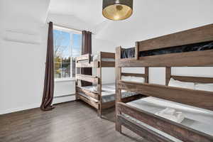 Bedroom with wood finished floors, lofted ceiling, and an AC wall unit