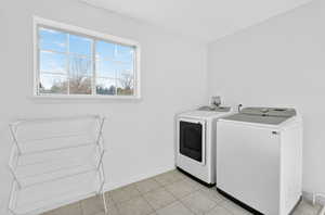 Laundry area with light tile patterned flooring and washer and dryer