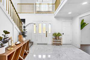 Entrance foyer featuring marble look tiles, stairway, a high ceiling, and recessed lighting