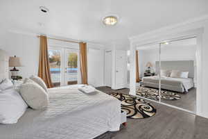 Bedroom featuring crown molding, wood finished floors, french doors, access to outside, and a wall mounted air conditioner