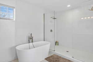 Full bath featuring a freestanding tub, walk in shower, and tile walls