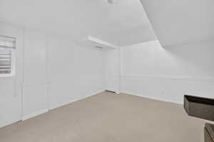 Bonus room featuring light carpet and a wainscoted wall