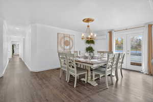 Dining area with ornamental molding, wood finished floors, and a chandelier