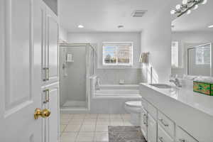 Bathroom featuring vanity, a bath, light tile patterned floors, a stall shower, and recessed lighting