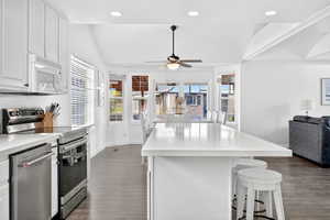 Kitchen with white cabinetry, open floor plan, appliances with stainless steel finishes, a center island, and dark wood-style flooring