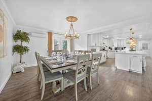 Dining area with a chandelier, light wood-style floors, ornamental molding, and a wall mounted AC