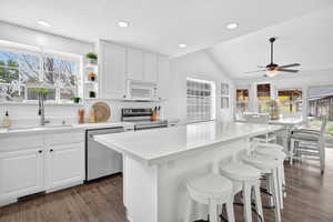 Kitchen with white cabinets, open shelves, dark wood finished floors, a breakfast bar, and recessed lighting