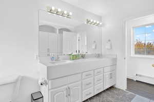 Bathroom with double vanity and a baseboard radiator