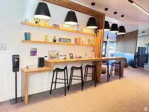 Bar area with wooden counters, hanging light fixtures, and light colored carpet