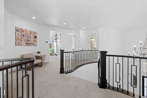 Hallway with an upstairs landing, carpet floors, recessed lighting, and a chandelier