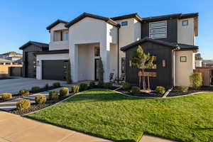 Modern home with brick siding, a front lawn, driveway, and a garage