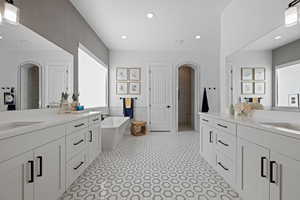 Bathroom with a freestanding tub, two vanities, recessed lighting, tile walls, and a wainscoted wall