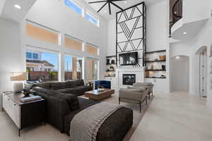 Living area featuring arched walkways, recessed lighting, a glass covered fireplace, and a towering ceiling