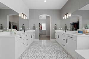 Full bathroom with a spacious closet, two vanities, and recessed lighting