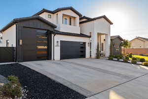 Contemporary home with concrete driveway, a standing seam roof, a metal roof, a garage, and a gate
