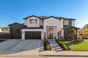 Modern home featuring brick siding, driveway, and a garage