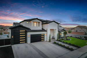 Modern home with concrete driveway, an attached garage, a standing seam roof, and a metal roof