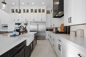 Kitchen with dark cabinets, tasteful backsplash, light stone countertops, built in appliances, and recessed lighting