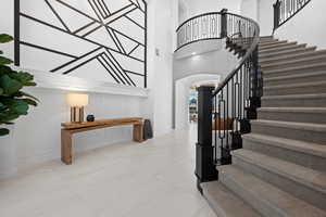 Stairs featuring arched walkways, a towering ceiling, and tile patterned flooring
