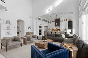 Living area featuring a towering ceiling, arched walkways, and carpet flooring