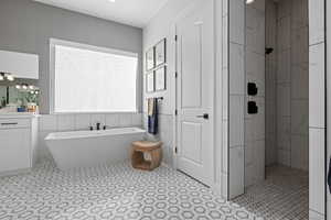 Bathroom with a soaking tub, tiled shower, vanity, and tile walls