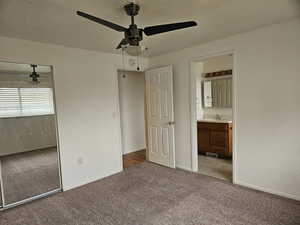 Master bedroom with light colored carpet, a textured ceiling, a closet, a ceiling fan, and ensuite bath