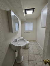 Basement 3/4 Bathroom featuring a textured wall, a textured ceiling, and light tile patterned floors