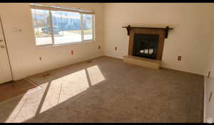 Unfurnished living room featuring carpet flooring and a tile fireplace