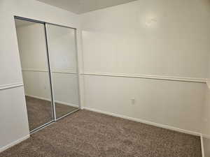 Unfurnished bedroom featuring dark colored carpet, a closet, and a textured ceiling