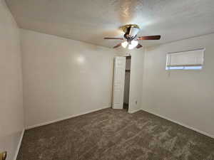 Basement Bedroom featuring dark colored carpet, a textured ceiling, and a ceiling fan