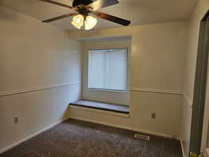 Carpeted empty room with ceiling fan and a textured ceiling
