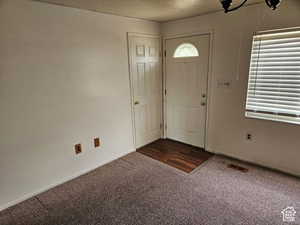 Entrance foyer with a textured ceiling and dark carpet