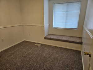 Spare room featuring dark colored carpet and baseboards