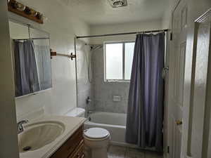 Upstairs Bathroom with a textured ceiling, vanity, shower / tub combo, and light tile patterned flooring