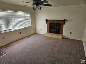 Unfurnished living room with carpet flooring, a fireplace, a textured ceiling, and ceiling fan