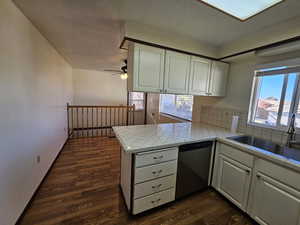Kitchen featuring tile counters, white cabinetry, dishwasher, dark wood-style floors, and a textured ceiling