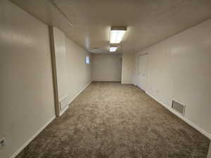 Basement with carpet flooring and a textured ceiling